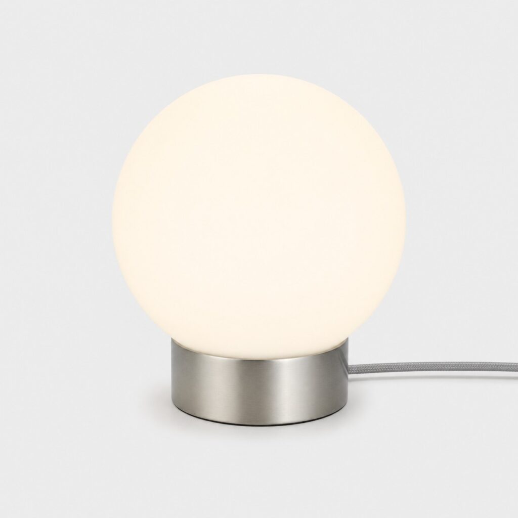 Lampe de chevet tactile à globe en verre opale et pied nickel mat sur fond gris clair